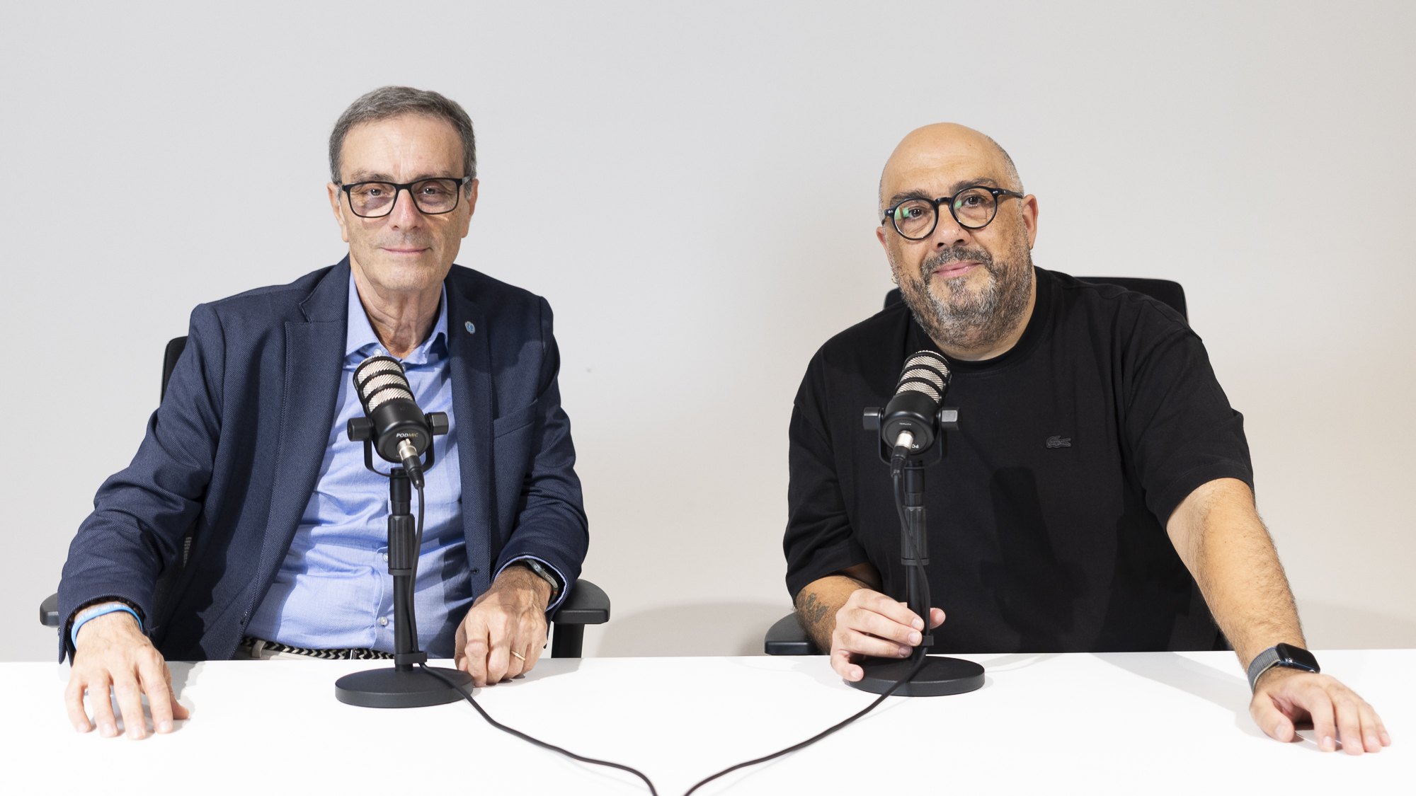 Tre conduttori al tavolo con i microfoni durante una puntata del podcast