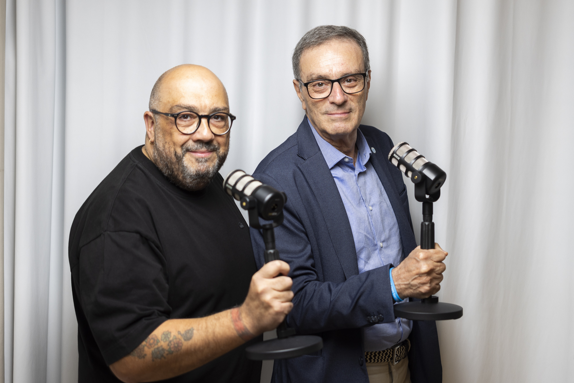 Tre conduttori al tavolo con i microfoni durante una puntata del podcast