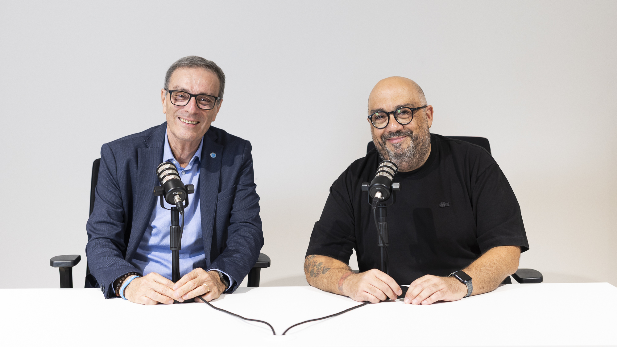 Tre conduttori al tavolo con i microfoni durante una puntata del podcast